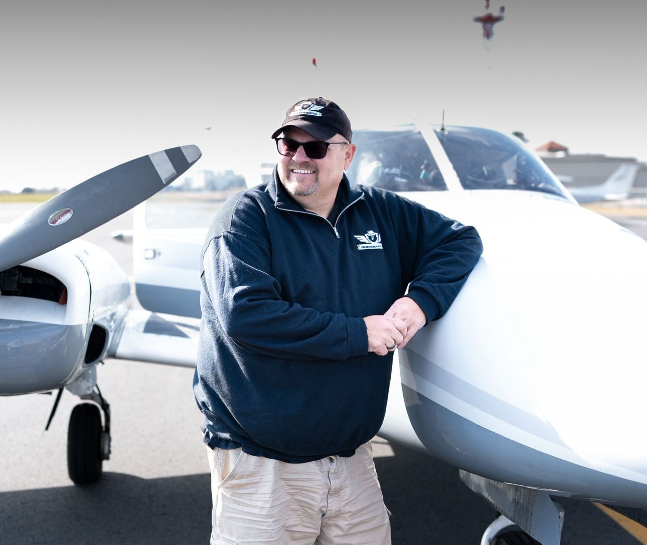 Two men are standing in front of a small plane.