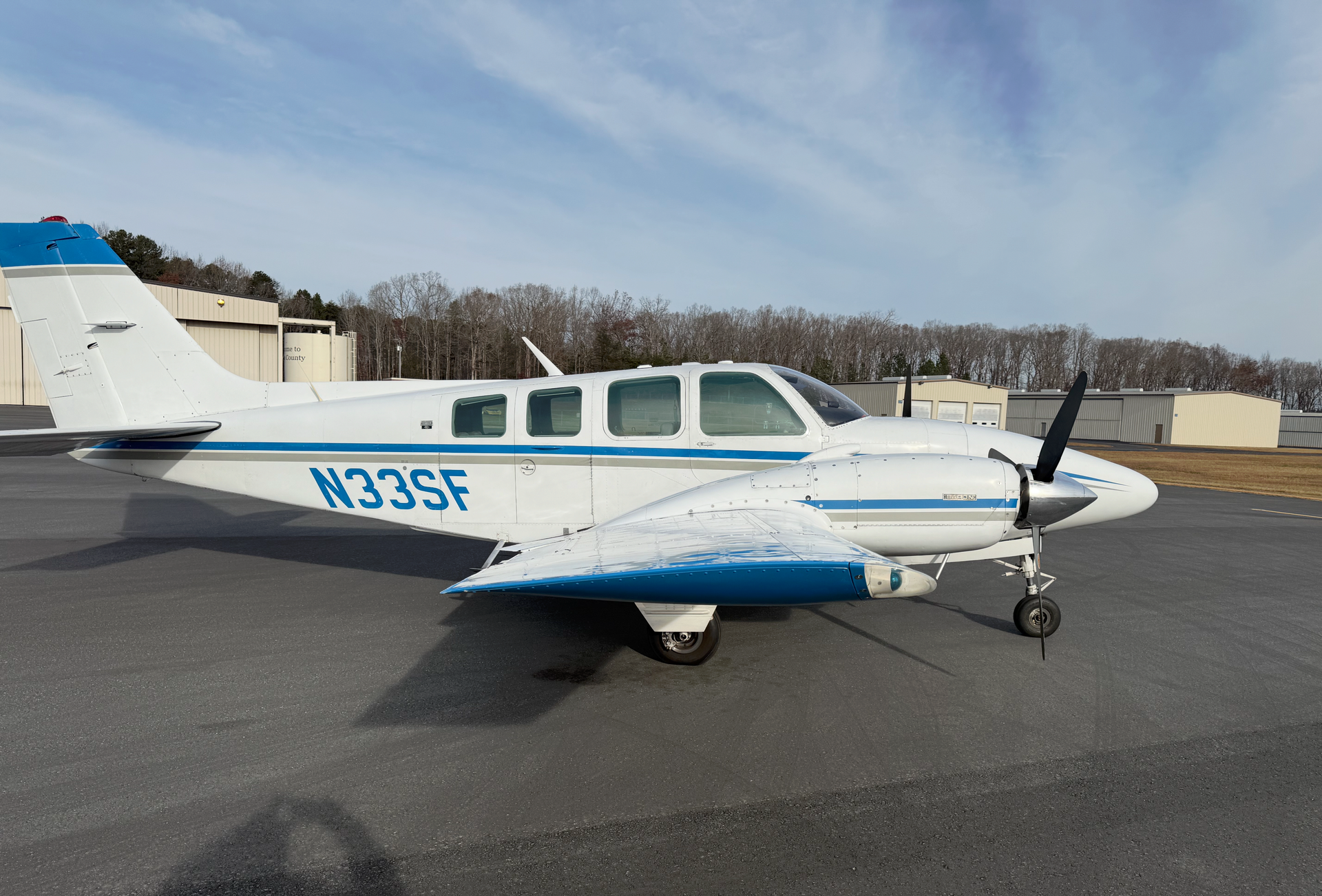 Small white-and-blue single-engine airplane parked on a runway under a clear sky