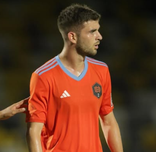 Um jovem de camisa listrada está jogando futebol em um campo.