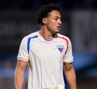 Um homem vestindo uma camisa de pari está em um campo