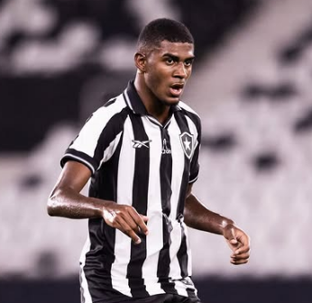 Um jovem com uma camisa de futebol com listras brancas e pretas está correndo em um campo.