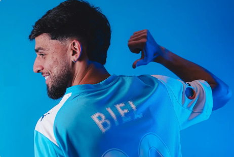 Um jogador de futebol vestindo uma camisa listrada de vermelho e azul com a letra s