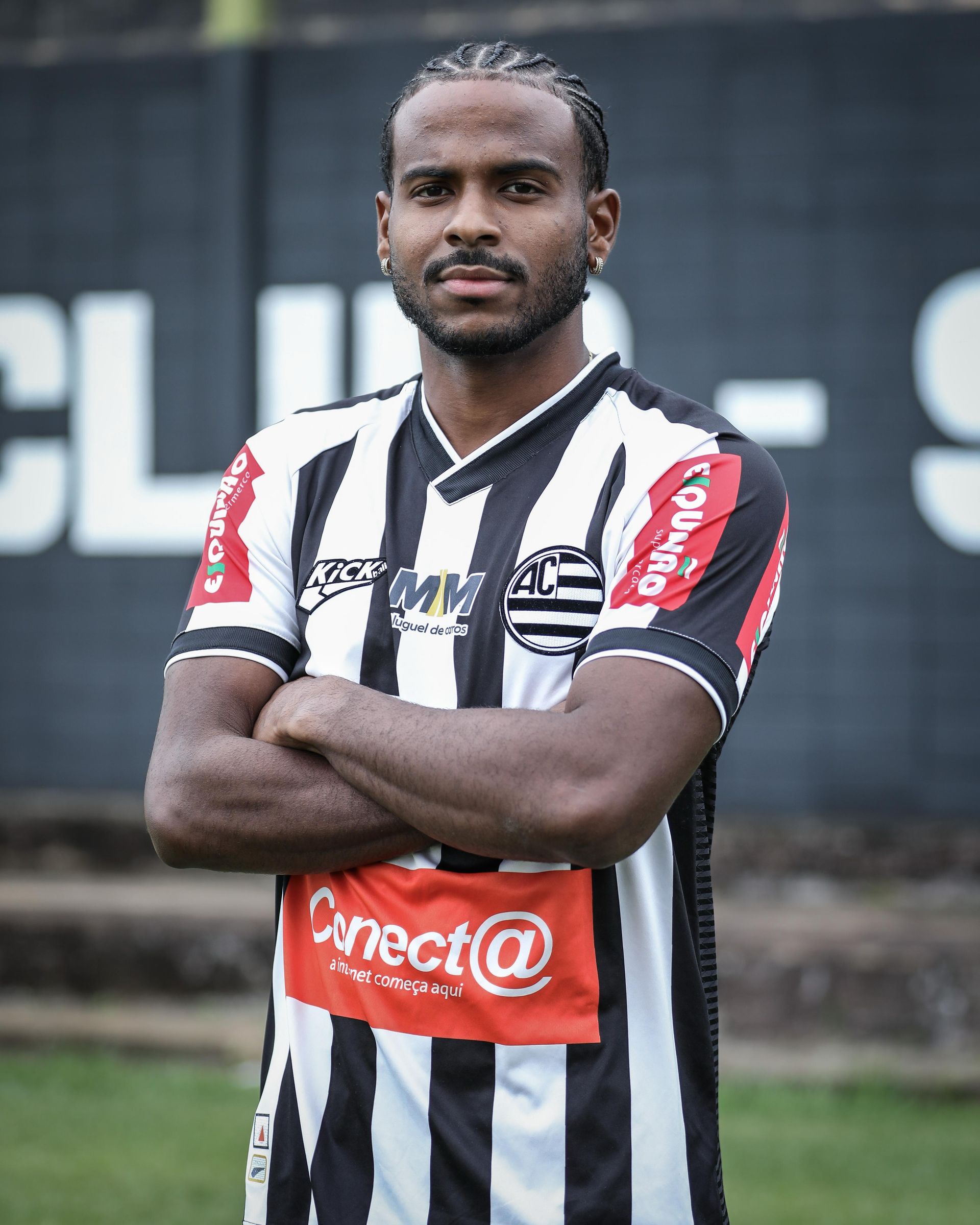 Um jogador de futebol com camisa roxa está correndo em um campo.