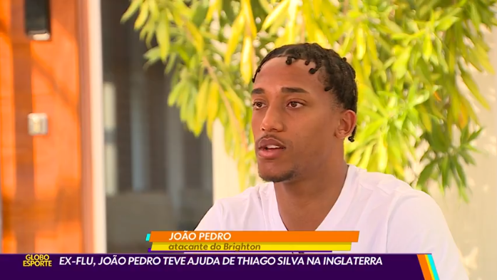 Um homem de camisa branca está sentado em frente a uma árvore.