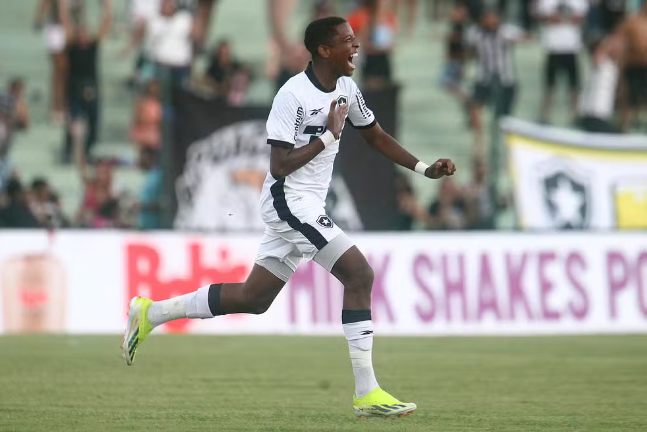 Um jogador de futebol está correndo na frente de uma faixa que diz shakes
