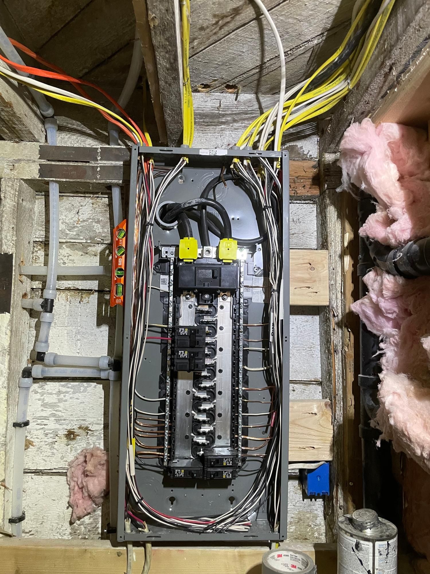Electrical panel with numerous wires in a basement.