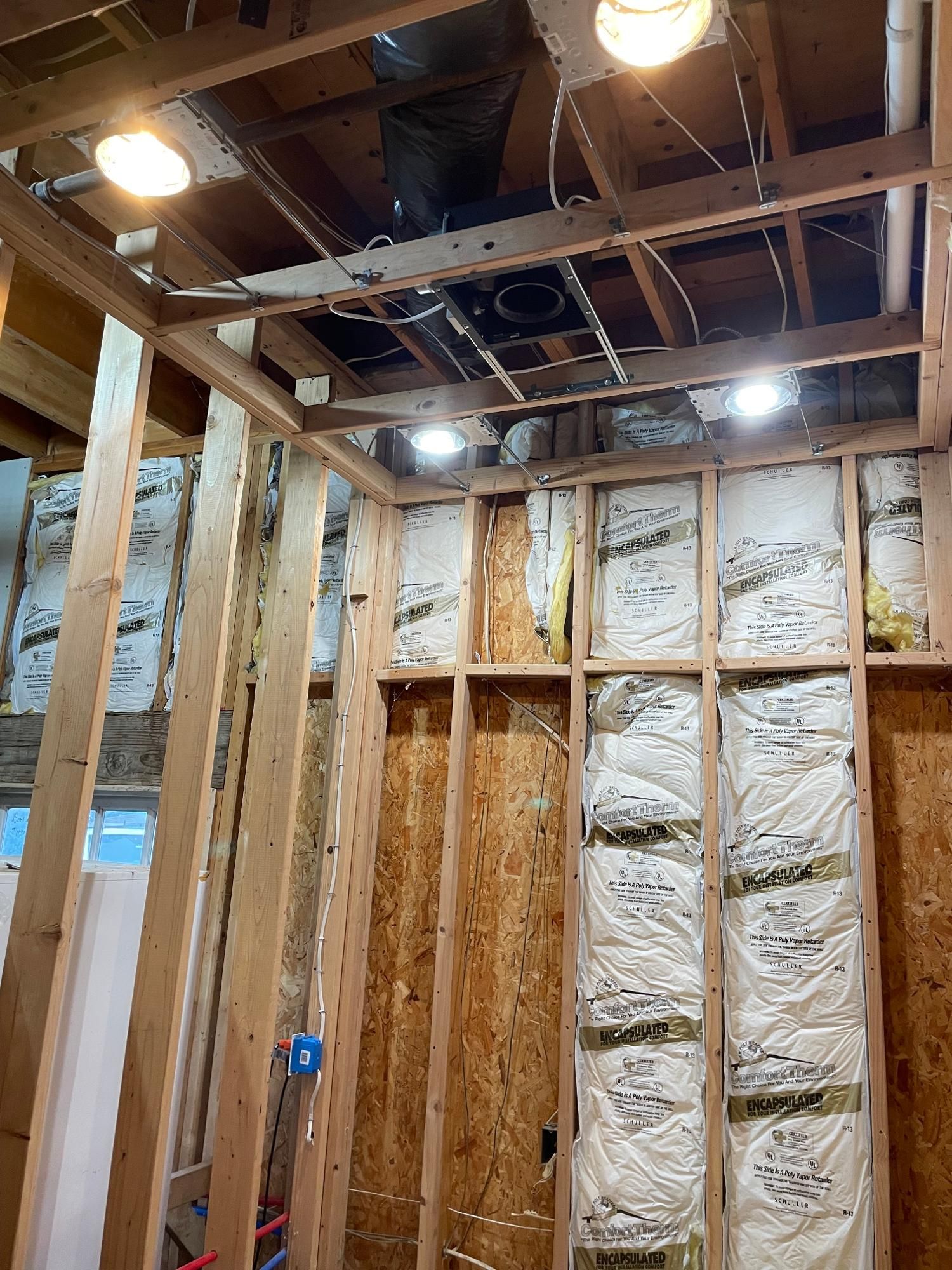 Interior construction; exposed wooden studs, insulation, and wiring; recessed lighting fixtures.