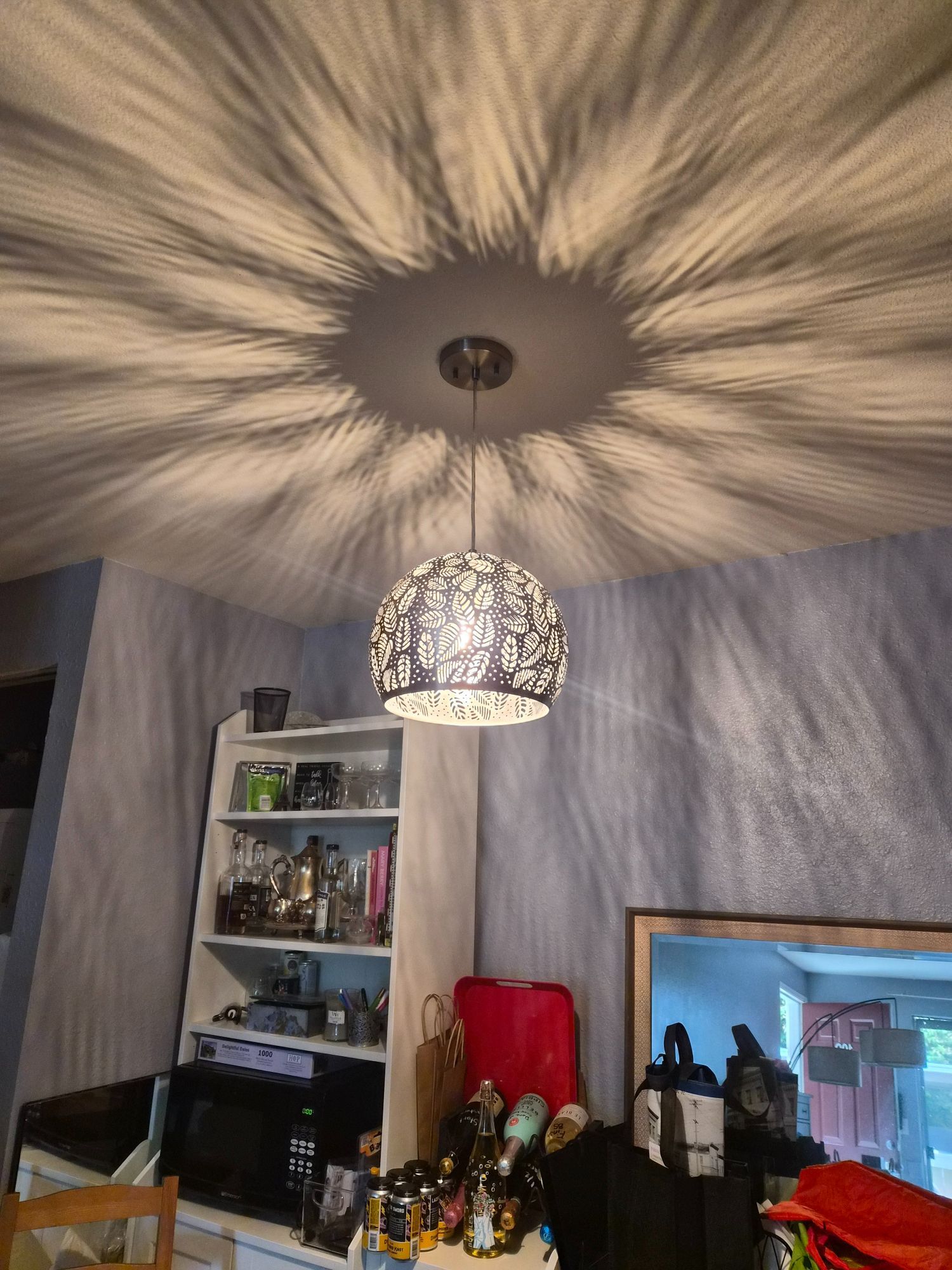 Living room with a patterned ceiling light casting starburst shadows over shelves and a TV.