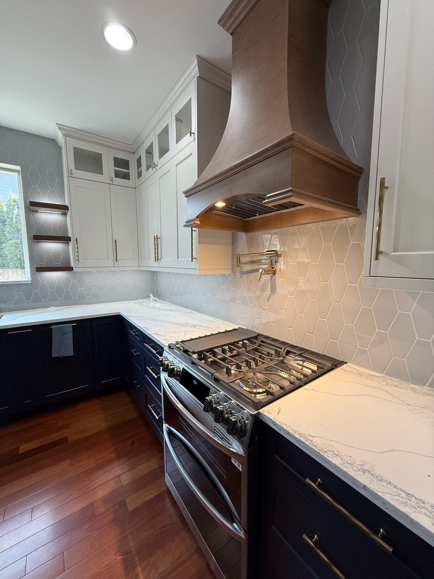 Modern kitchen with white cabinets, dark lower cabinets, gas range, copper hood, and marble-look backsplash