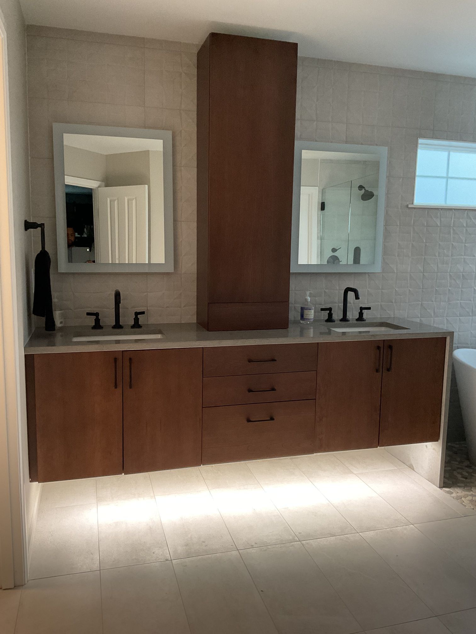 Modern bathroom vanity with double sinks, mirrors, wood cabinets, and under-cabinet lighting