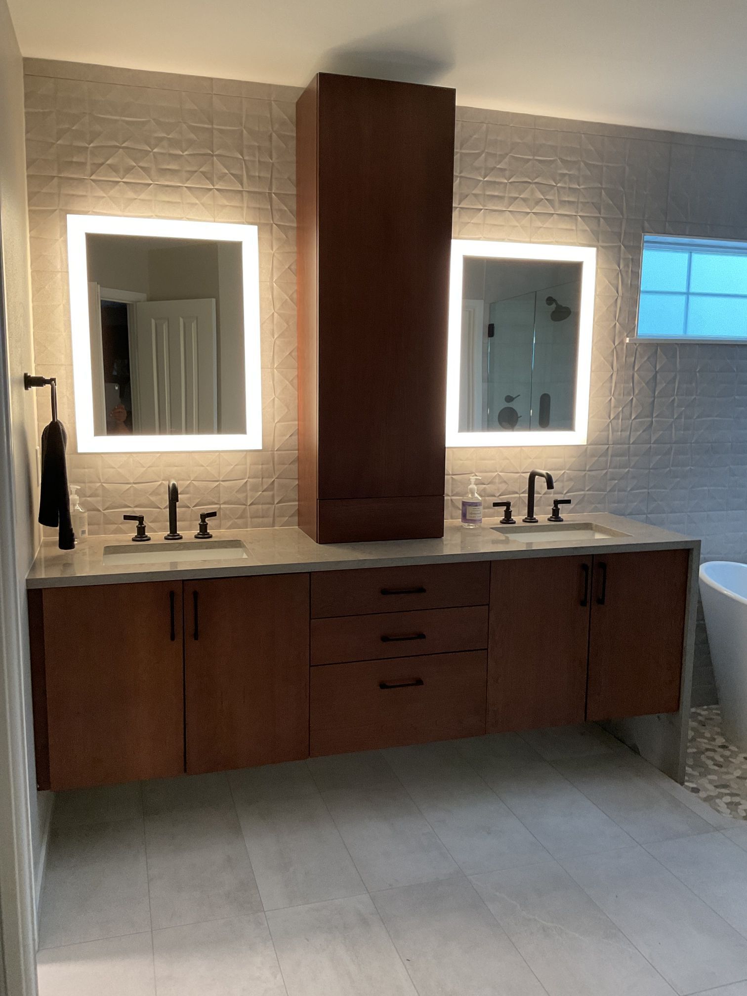 Modern double-sink bathroom vanity with backlit mirrors, wooden cabinets, and beige tile walls