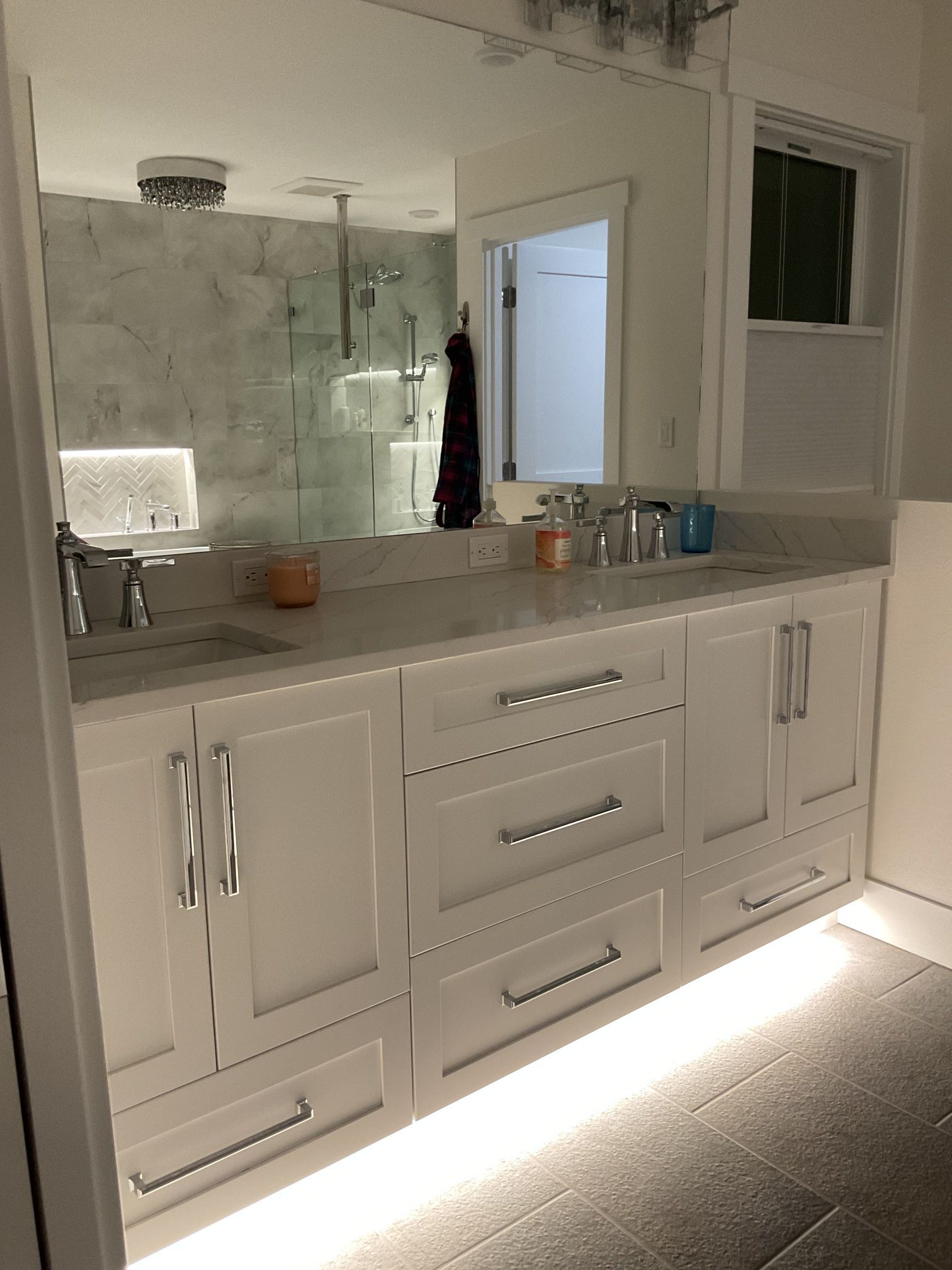 Modern white bathroom vanity with double mirrors, sink, and shower reflection in a bright room