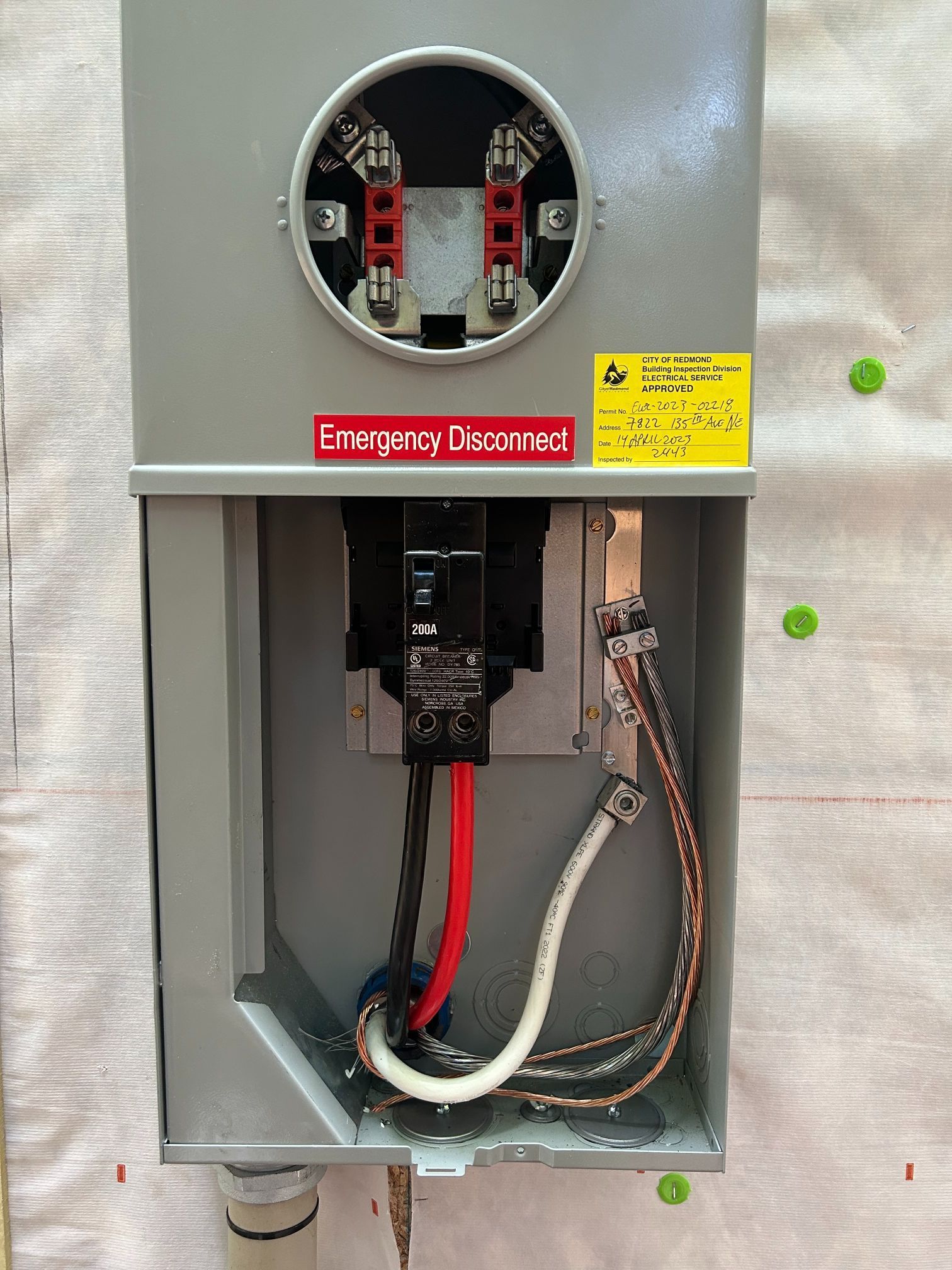 Open electrical breaker panel with exposed wiring and warning labels in a gray metal cabinet