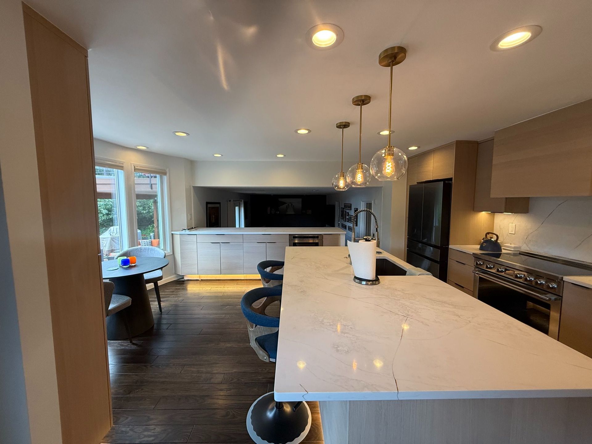 Modern kitchen with white island, dark cabinets, stainless appliances, and pendant lights
