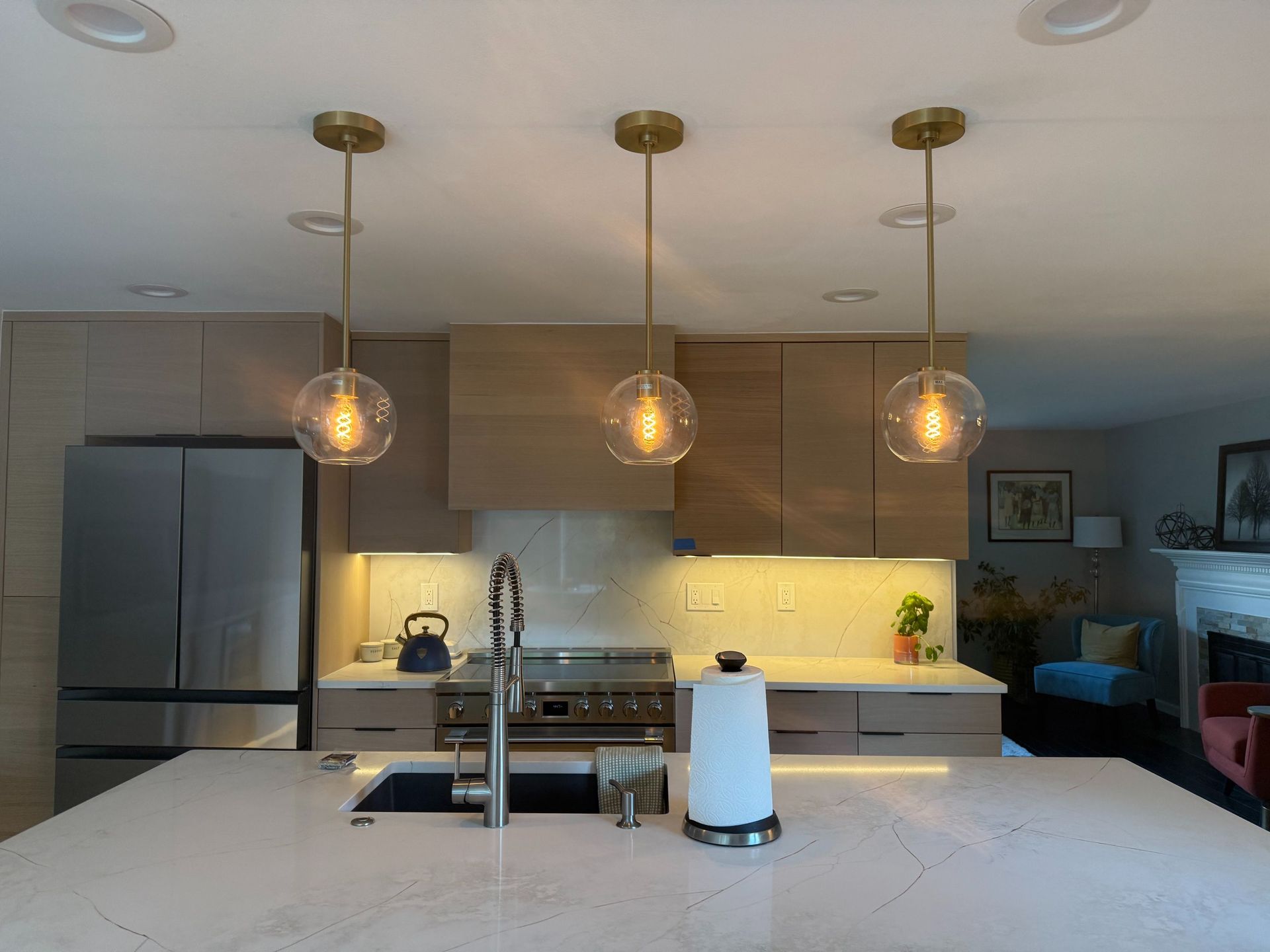 Modern kitchen with white island, pendant lights, stainless fridge, and a coffee maker on the counter
