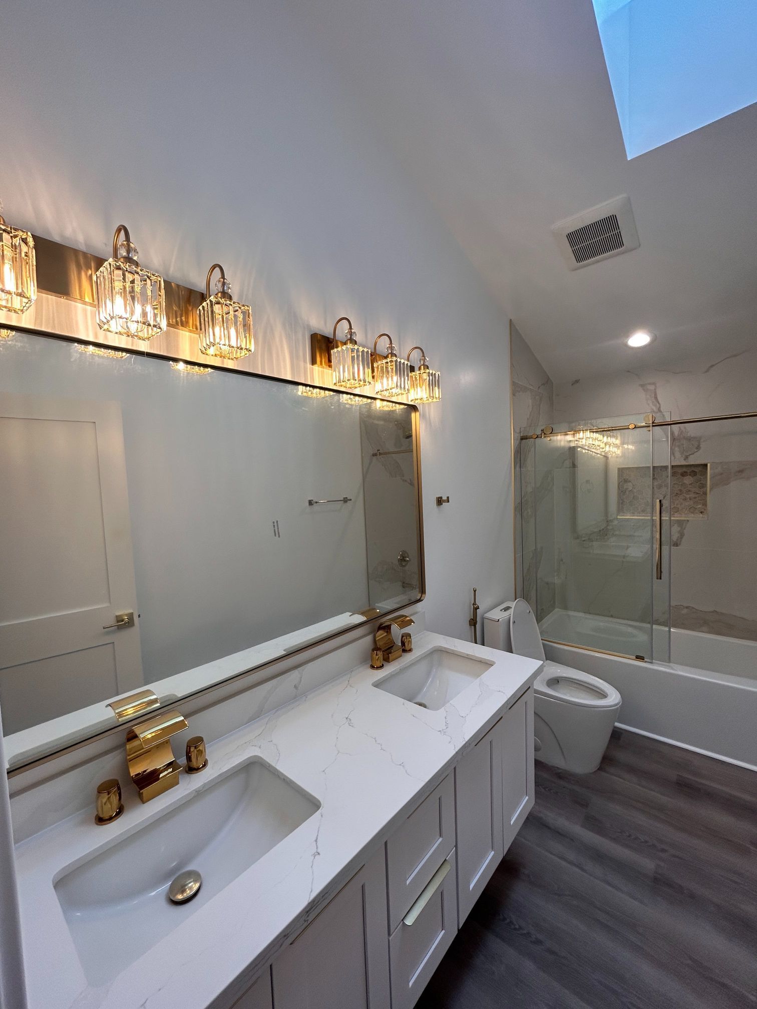 Modern bathroom with double vanity, large mirror, glass shower, and white finishes