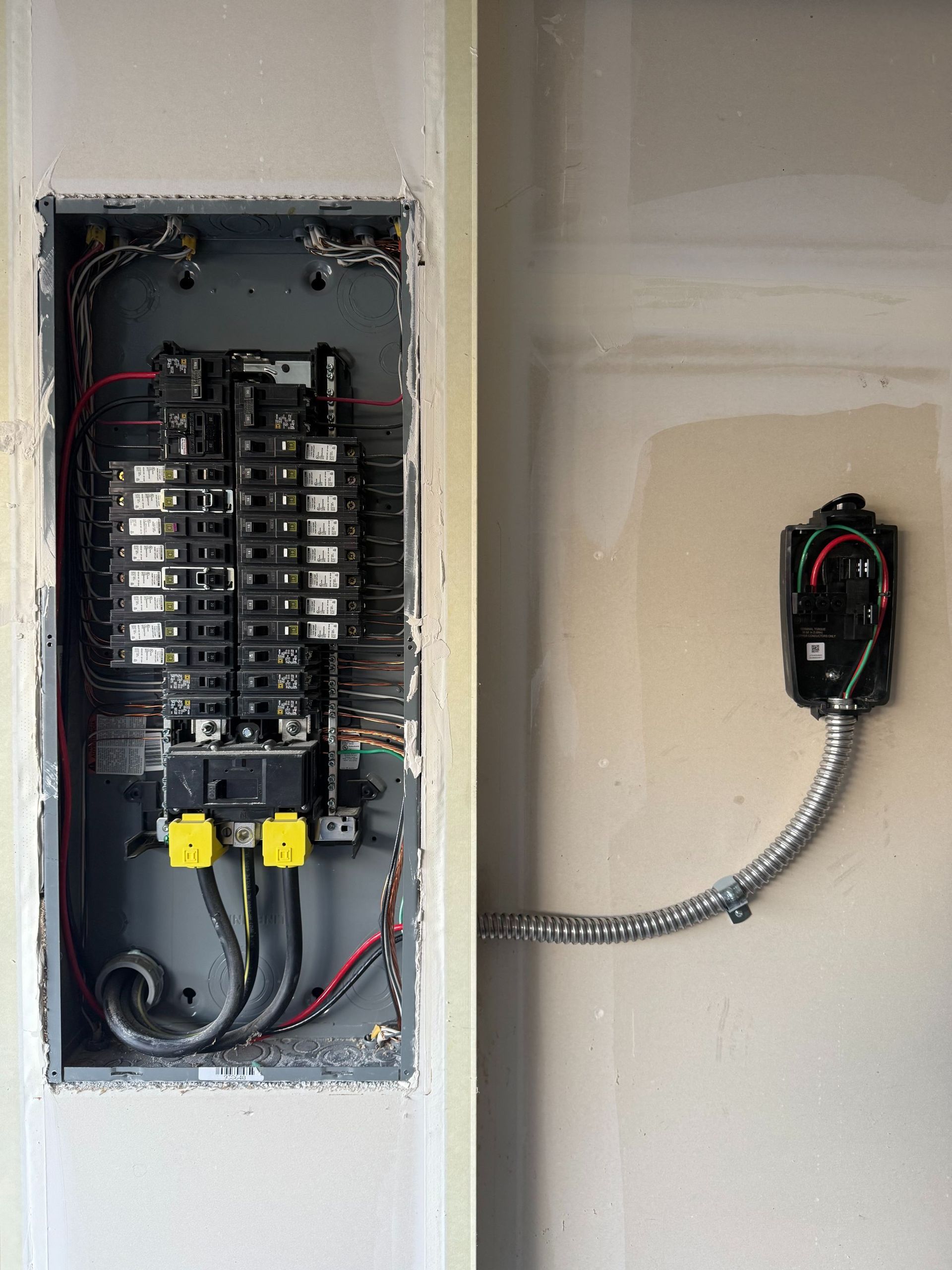 Open electrical breaker panel and wall-mounted device with conduit in a drywall room