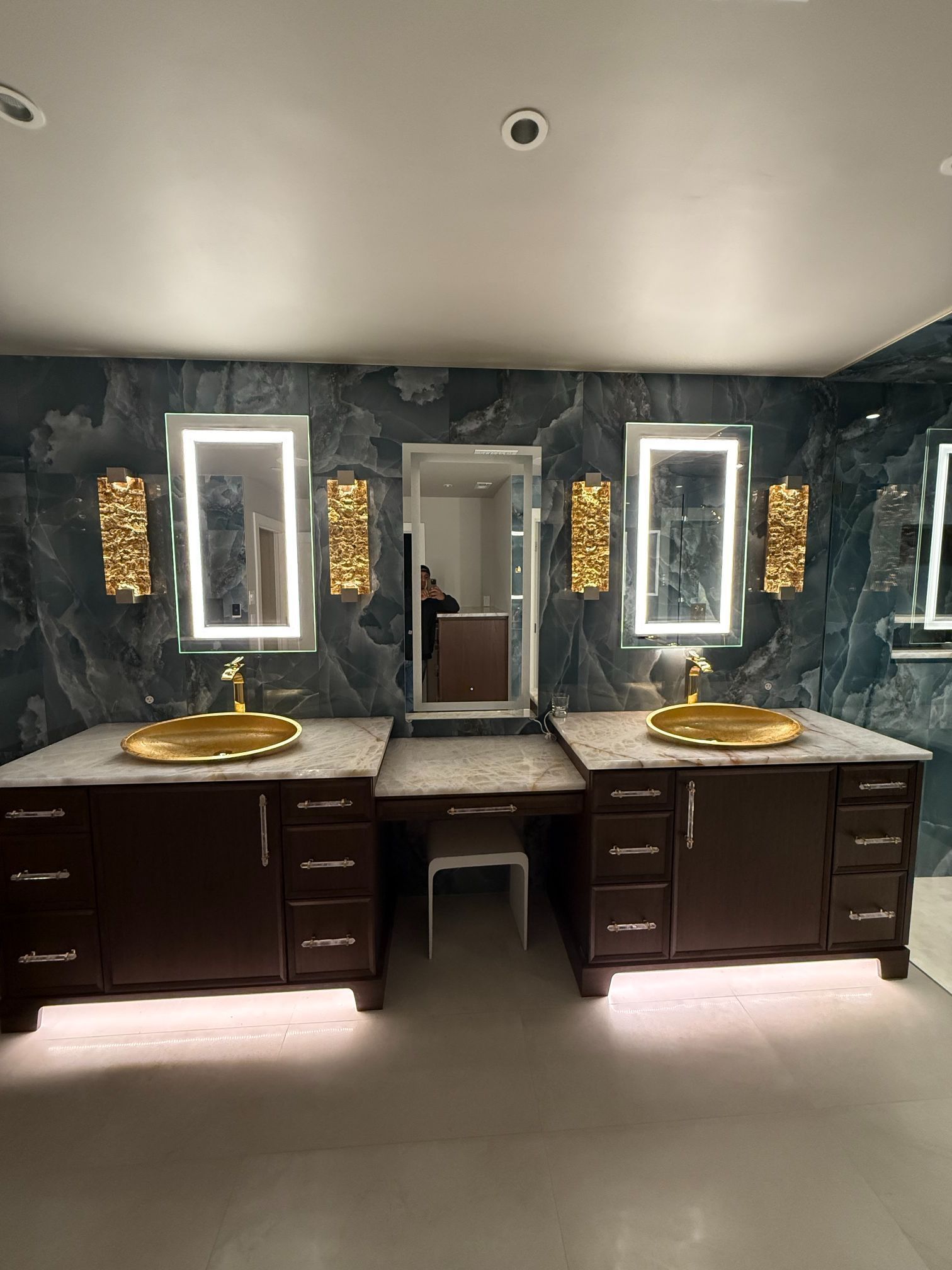 Double vanity bathroom with two sinks, mirrors, and dark wood cabinets on a patterned blue wall.