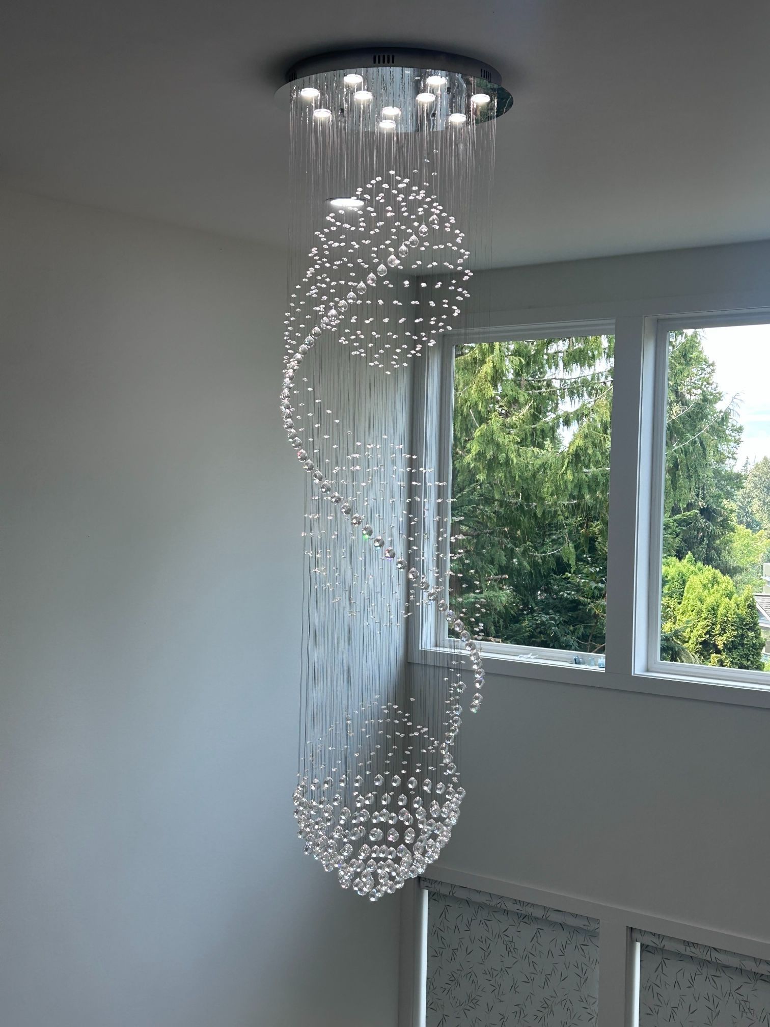 Modern spiral crystal ceiling light hanging in a bright room by a window