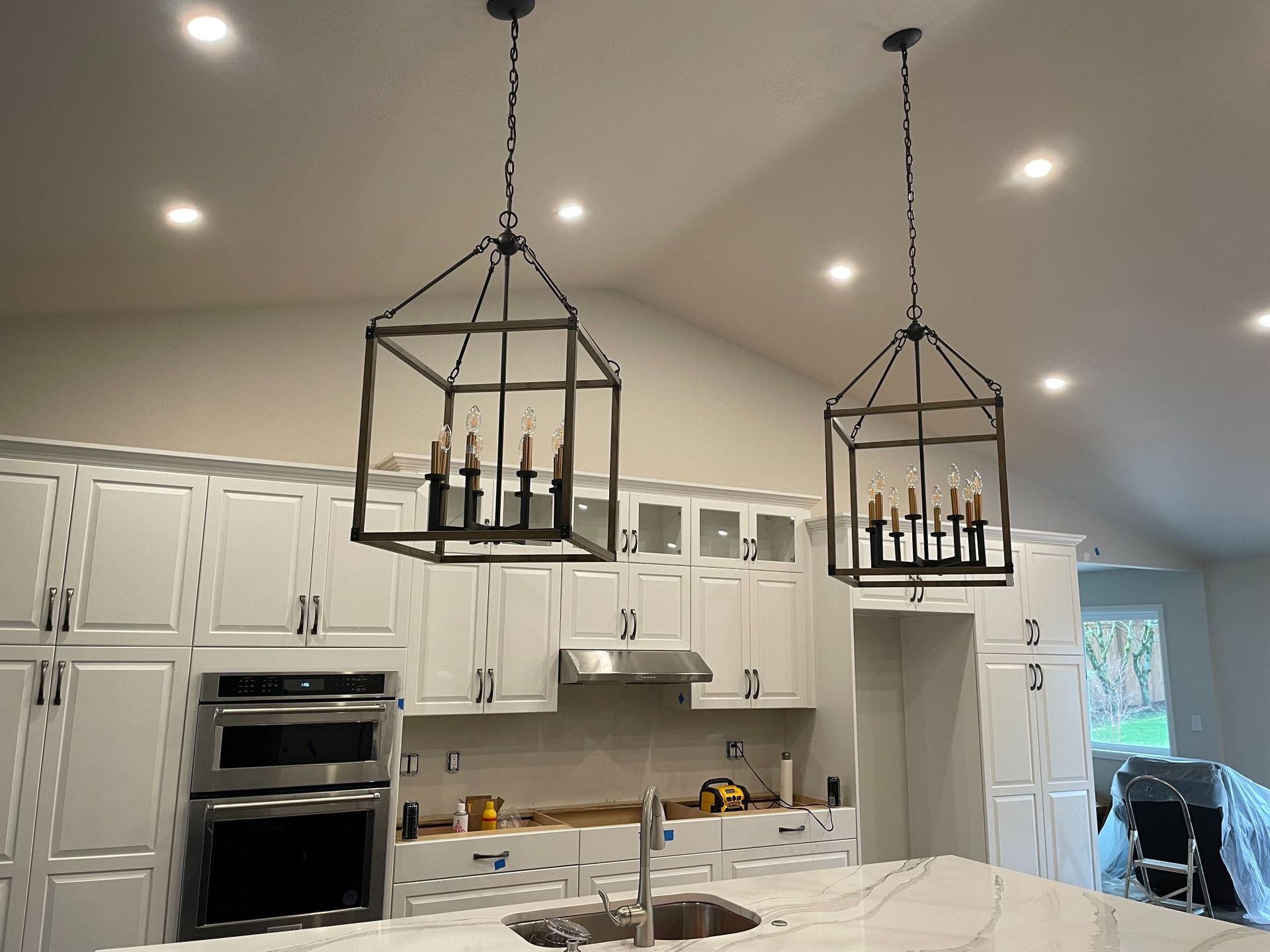 Bright white kitchen with two black geometric pendant lights over a large island.