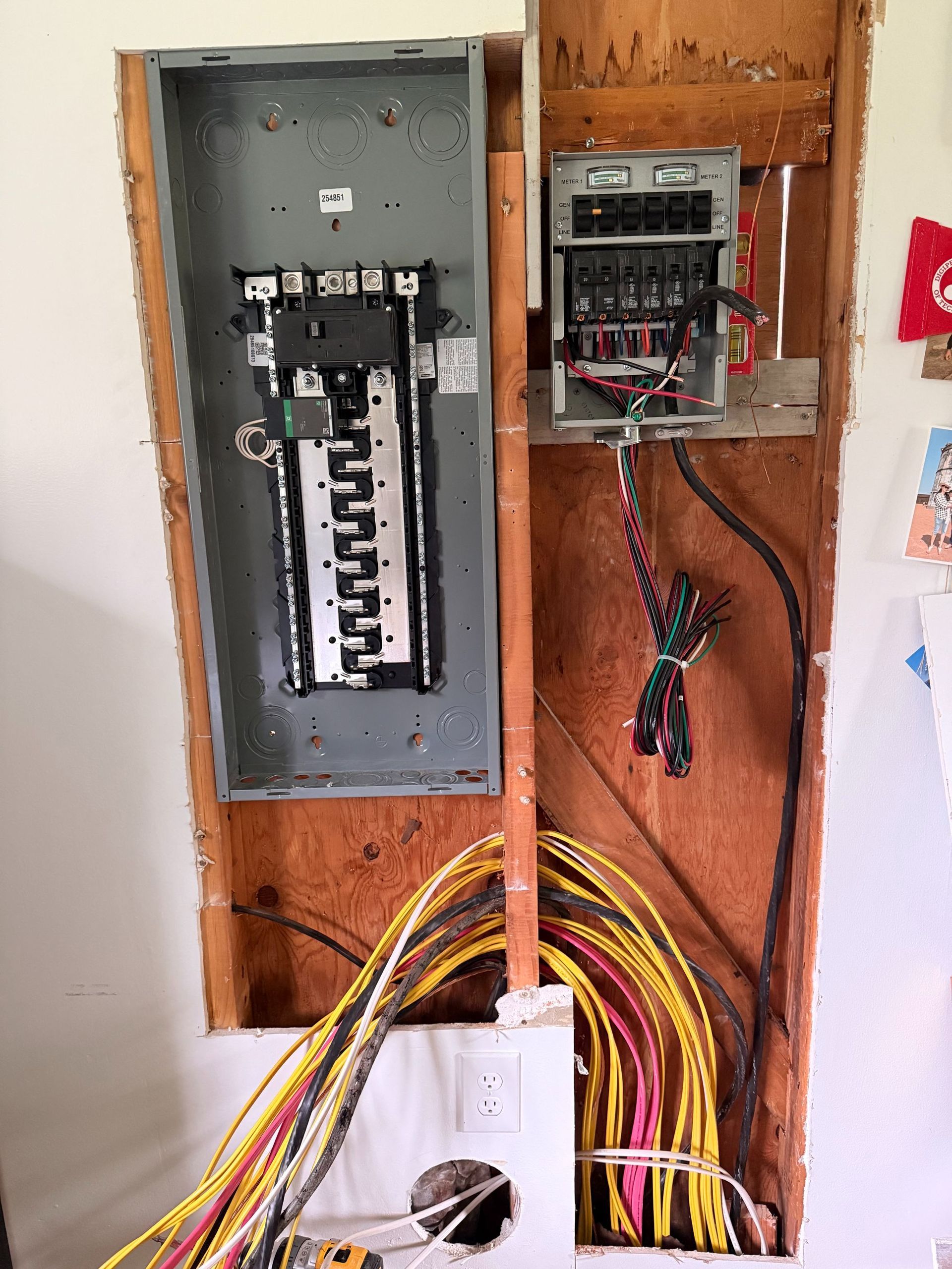 Open electrical panels with exposed wiring in a wall cavity during renovation