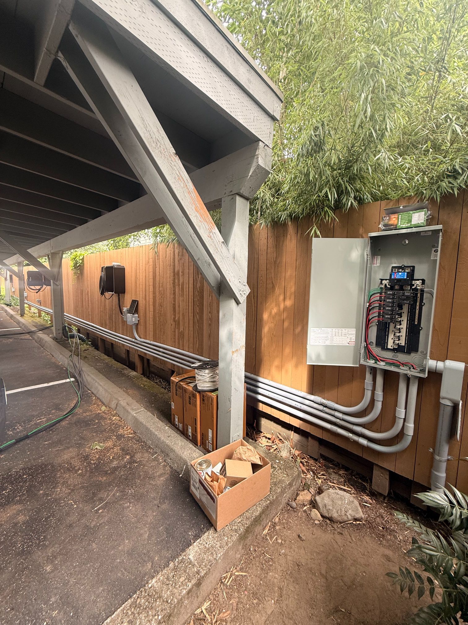 Backyard utility area with electrical panel, wooden fence, and covered patio support posts