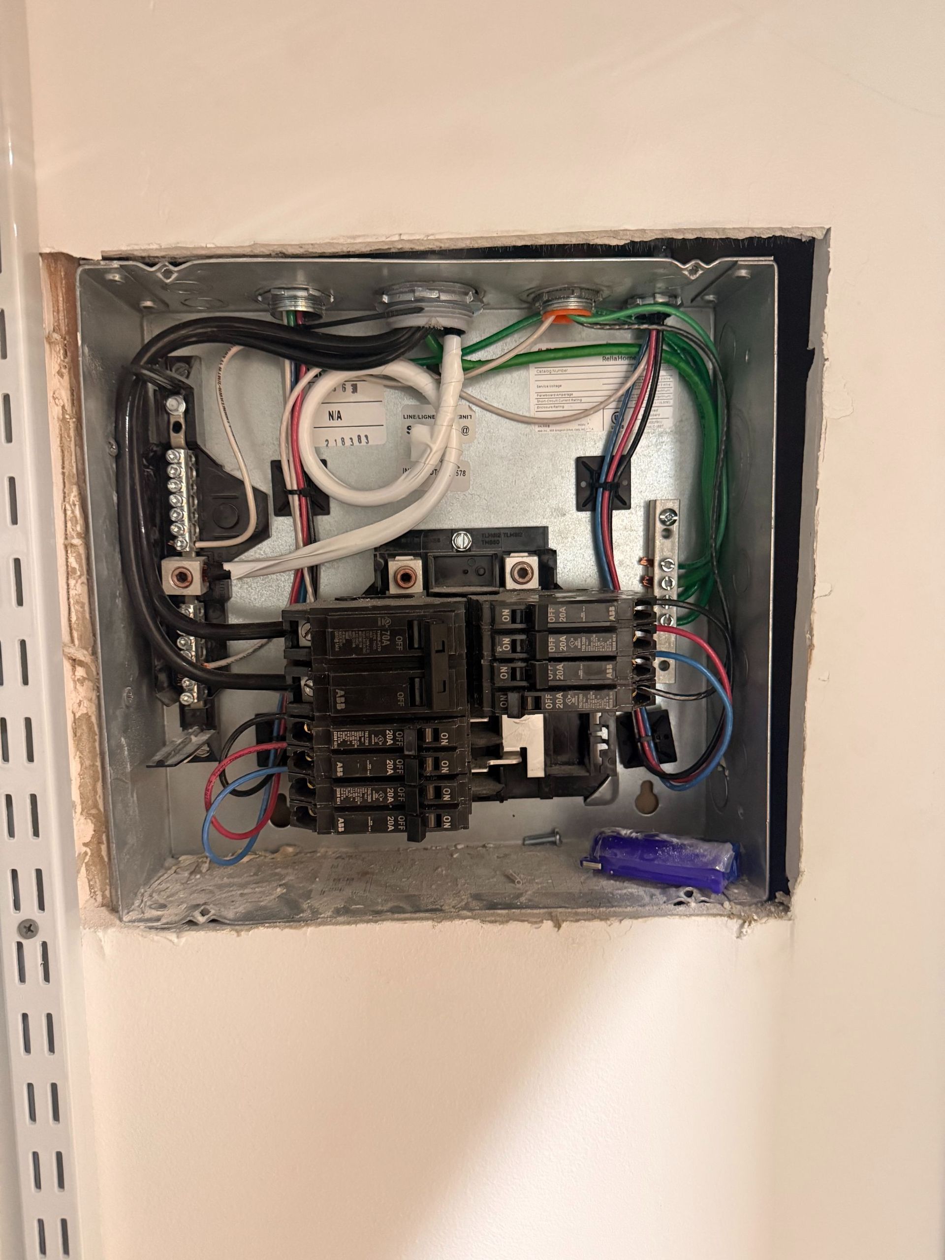 Open electrical breaker panel with exposed wiring and multiple circuit breakers in a wall recess