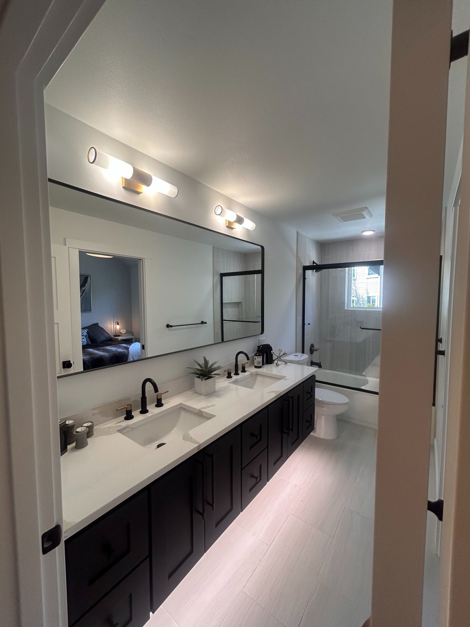 Modern bathroom with double vanity, large mirror, and bright white and black finishes