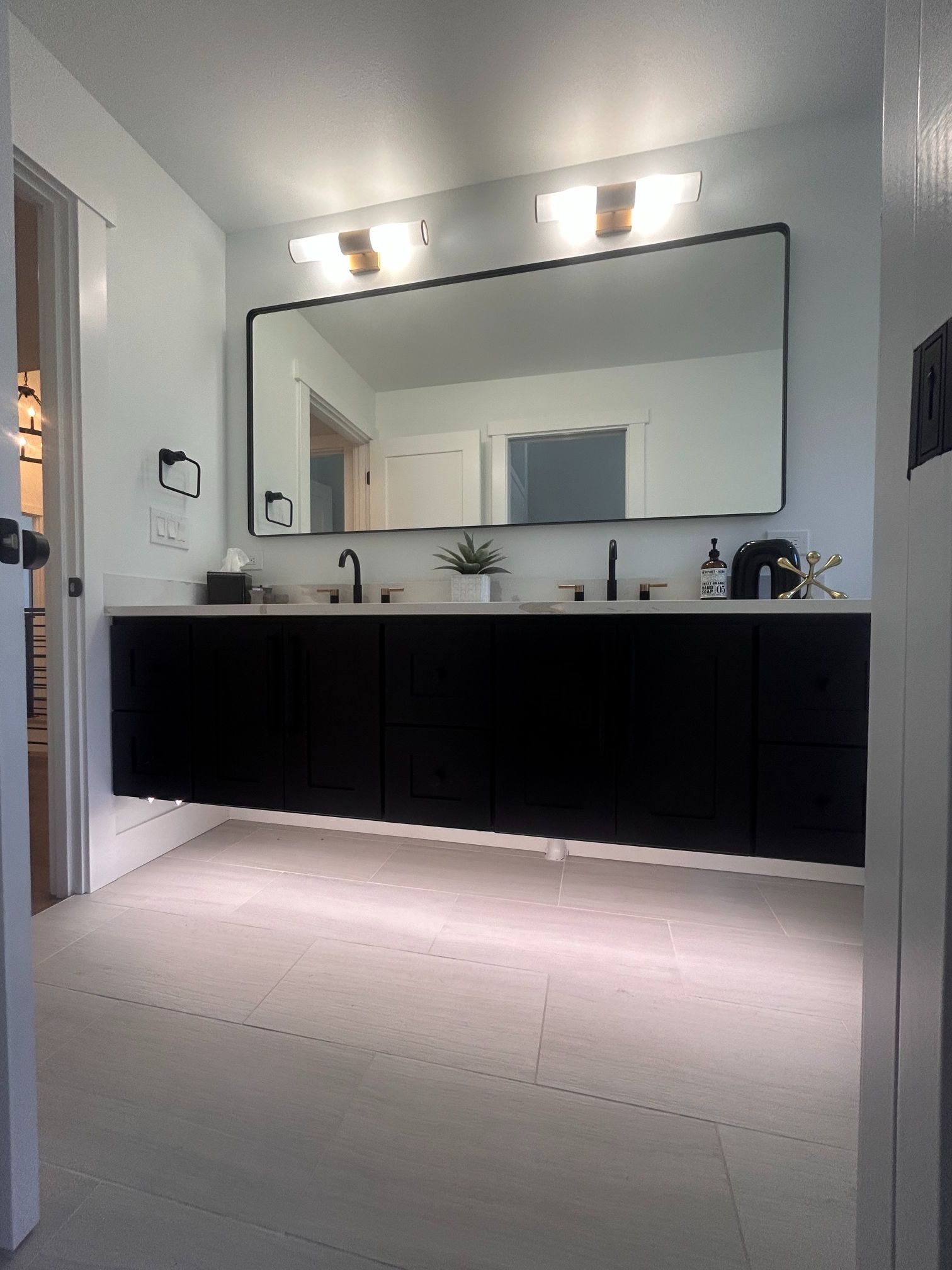 Modern bathroom with a large mirror, black vanity, and bright wall lights