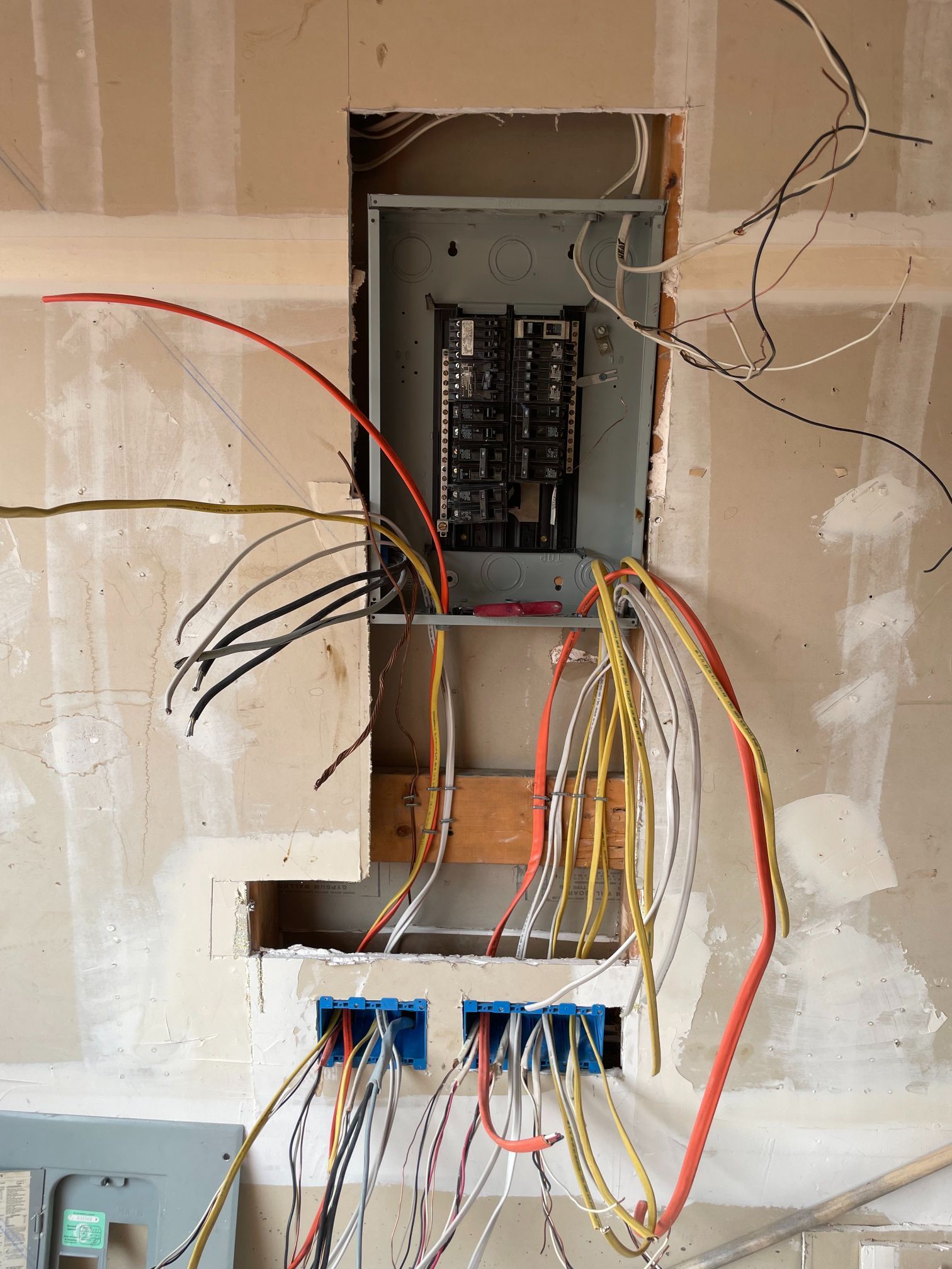 Open electrical panel with exposed wires in unfinished wall
