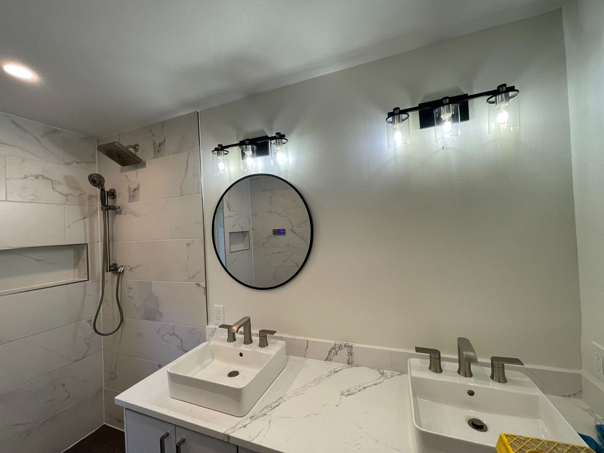 Modern bathroom with double sink, large mirror, wall sconces, and white marble tiles