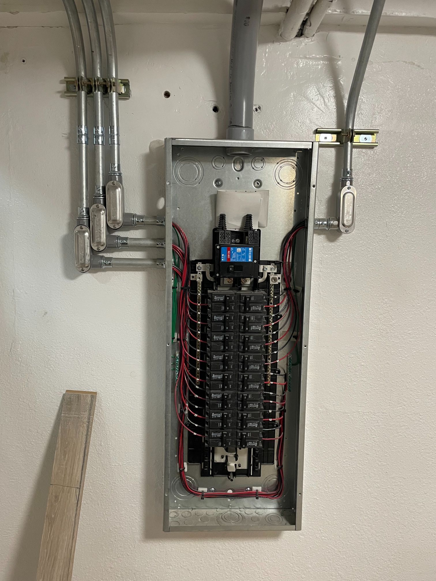 Open electrical breaker panel with exposed wiring in a utility room