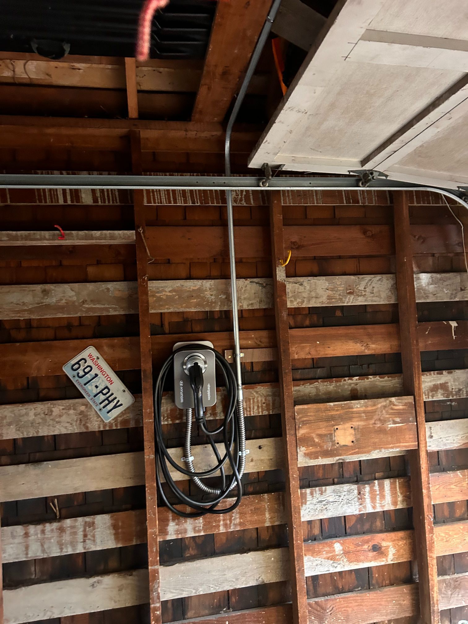 Interior of a wooden garage ceiling with exposed rafters, wiring, and an electrical outlet panel.