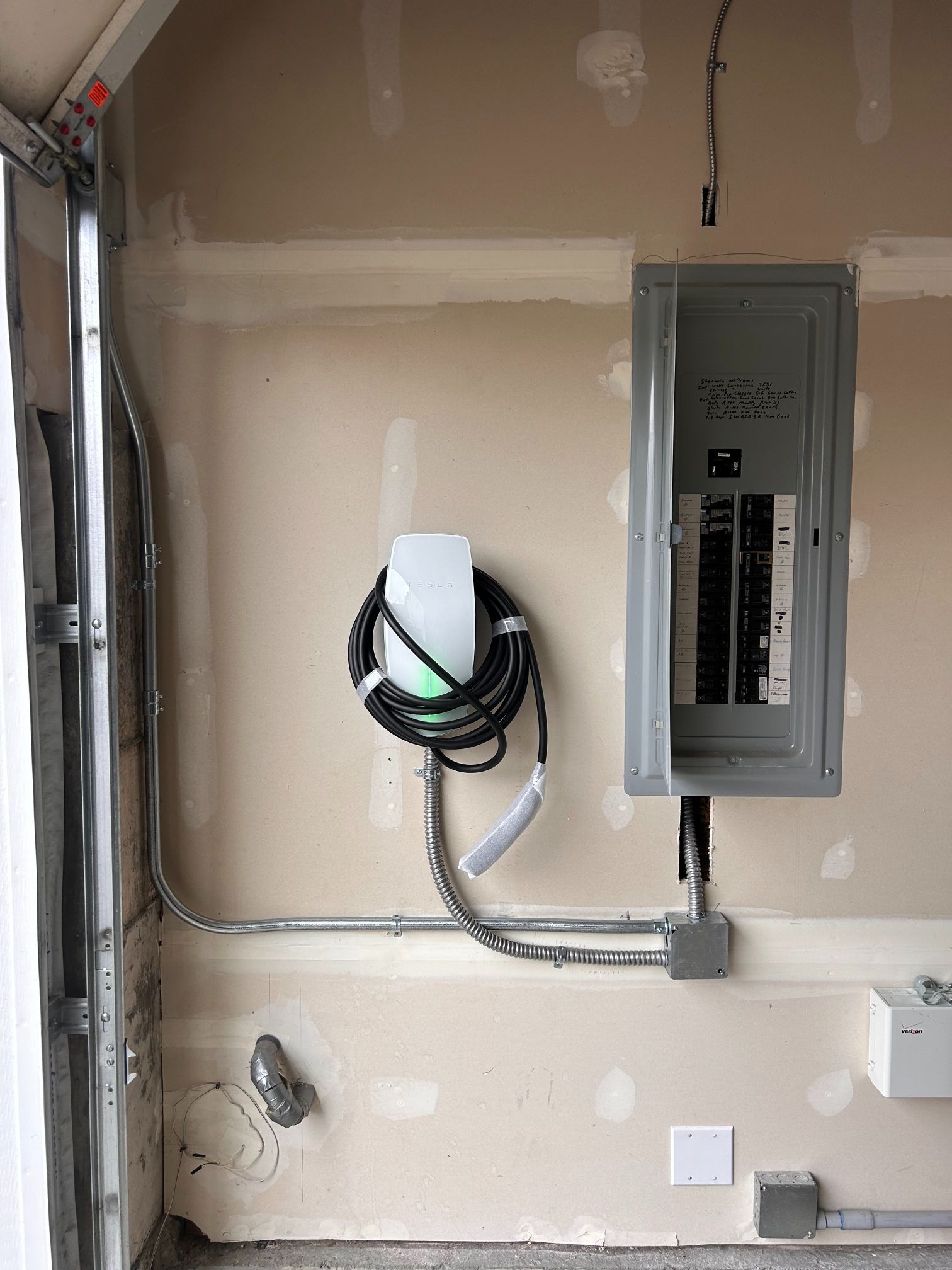 Electrical panel and exposed wiring in unfinished utility room interior.