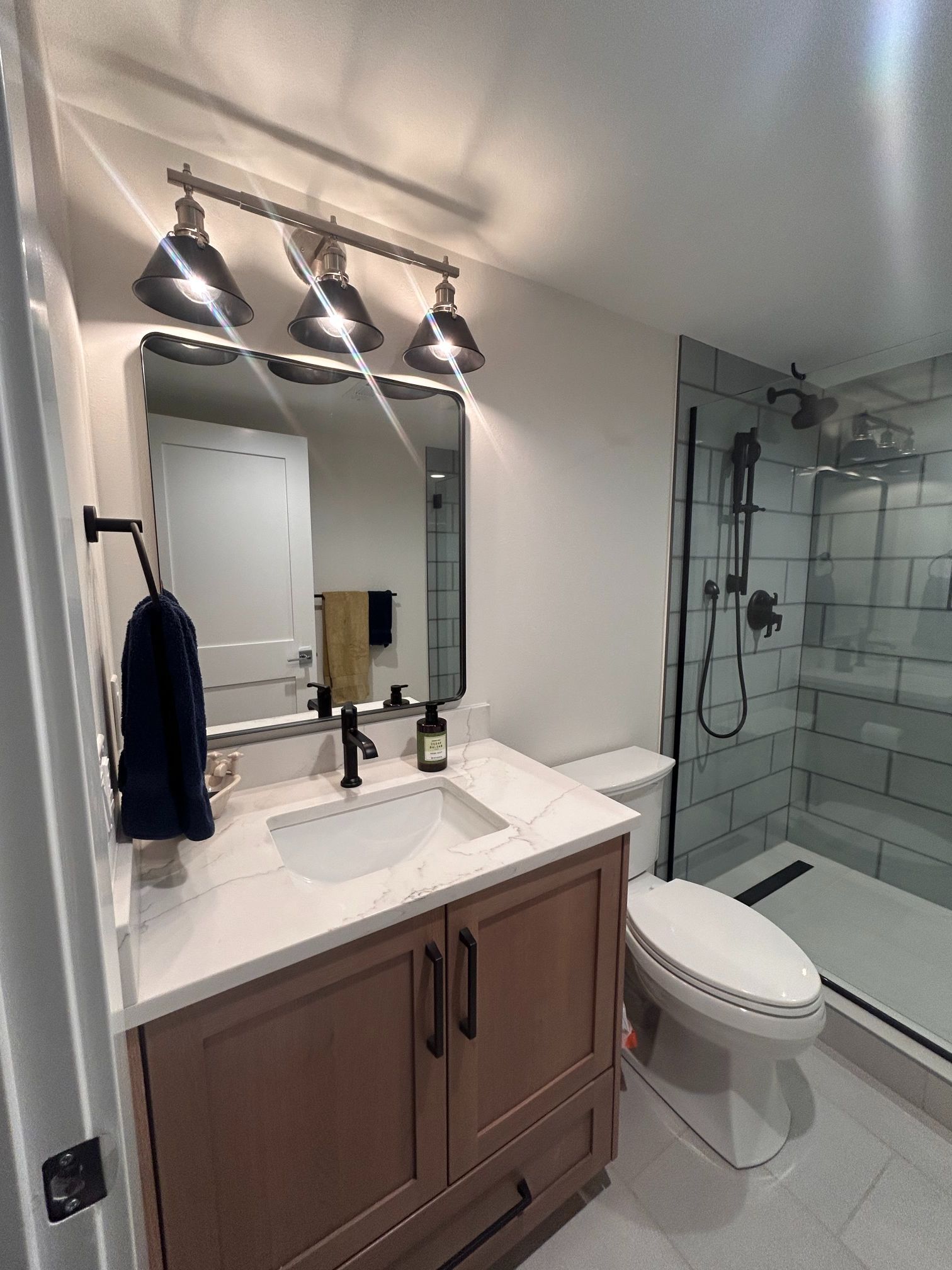 Modern bathroom with vanity, mirror, sink, toilet, and glass shower enclosure
