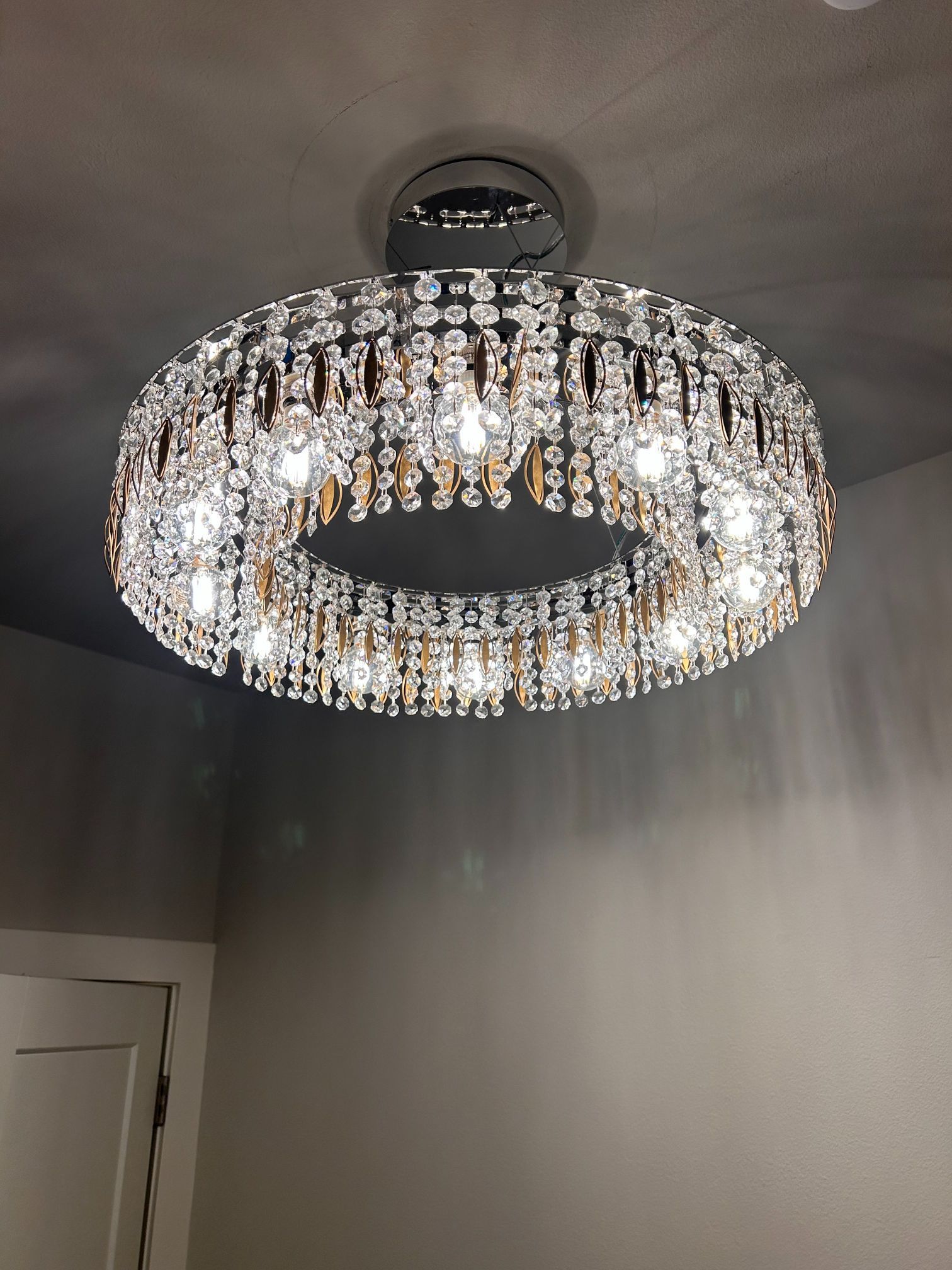 Crystal chandelier ceiling light in a gray room with a doorway visible below