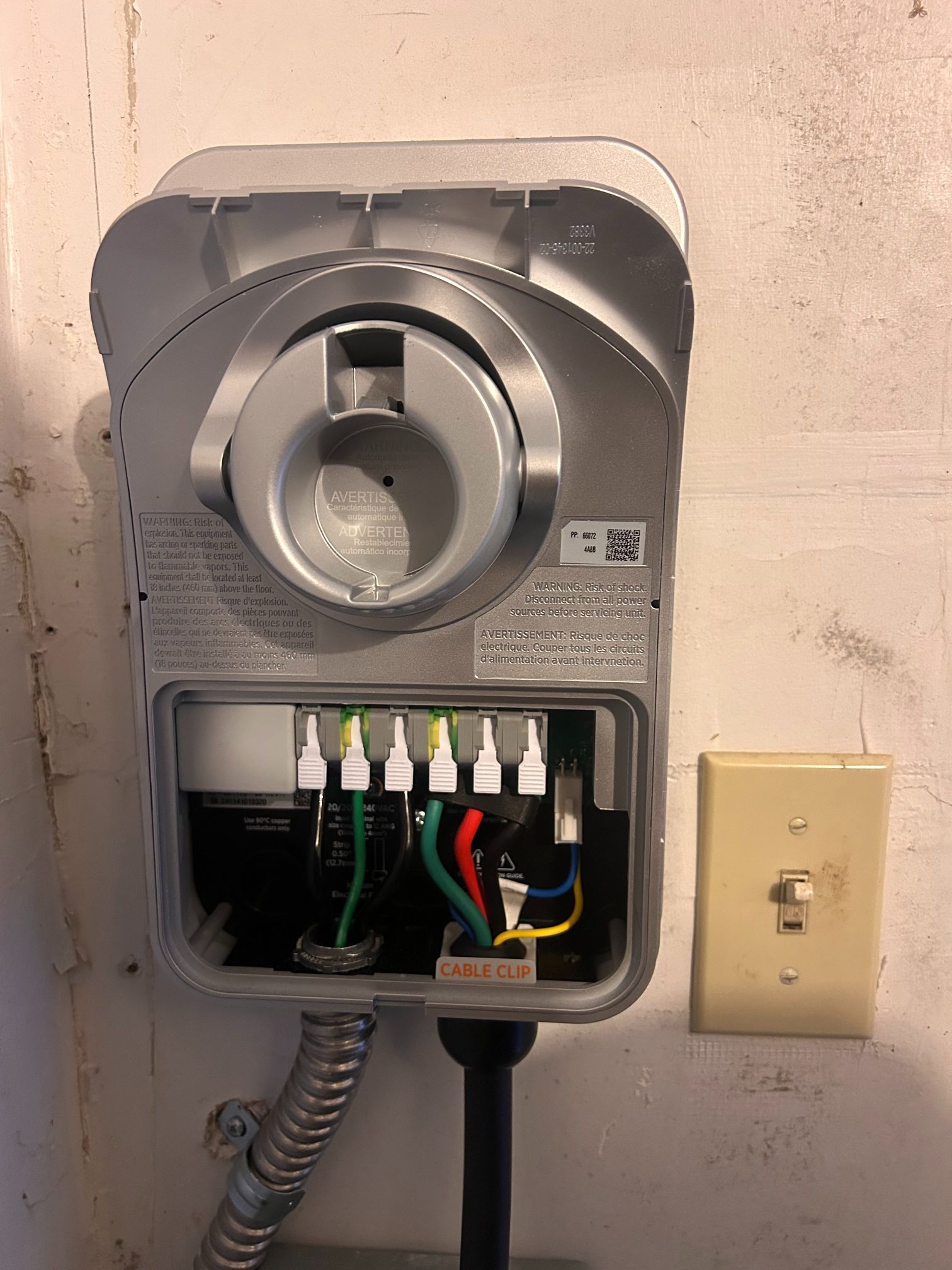 Open electrical box with exposed wiring and a wall light switch nearby.