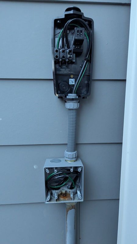 Open electrical meter and conduit mounted on gray house siding