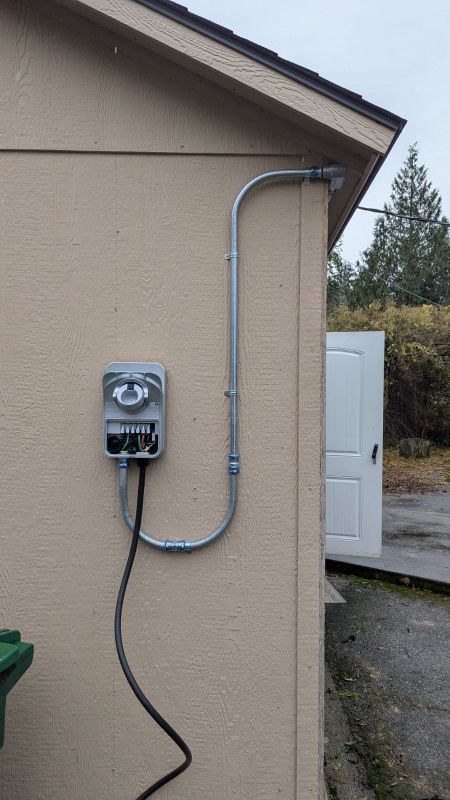 Electrical meter and conduit mounted on tan exterior wall beside an open white door.