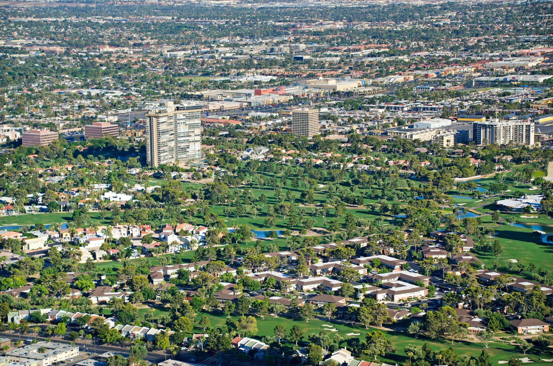 Aerial view of a city with a golf course, buildings, and green trees Aerial view of a city with a golf course, buildings, and green trees