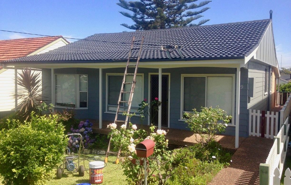 A Blue House With A Ladder In Front Of It Is Being Painted — In-Time Roofing In Newcastle, NSW