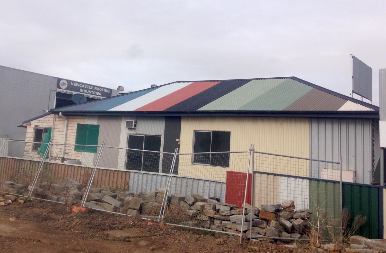 A House With A Colourful Roof And A Fence In Front Of It — In-Time Roofing In Newcastle, NSW