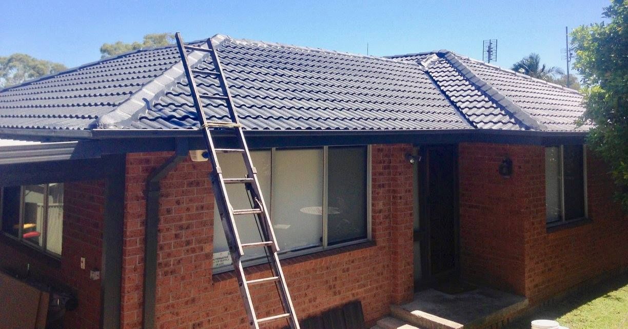 A Ladder Is Sitting On The Roof Of A Brick House — In-Time Roofing In Newcastle, NSW