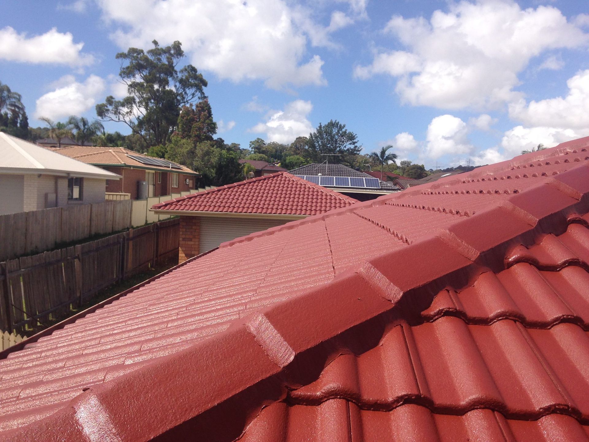 A Red Tiled Roof With A Blue Sky In The Background — In-Time Roofing In Lake Macquarie, NSW