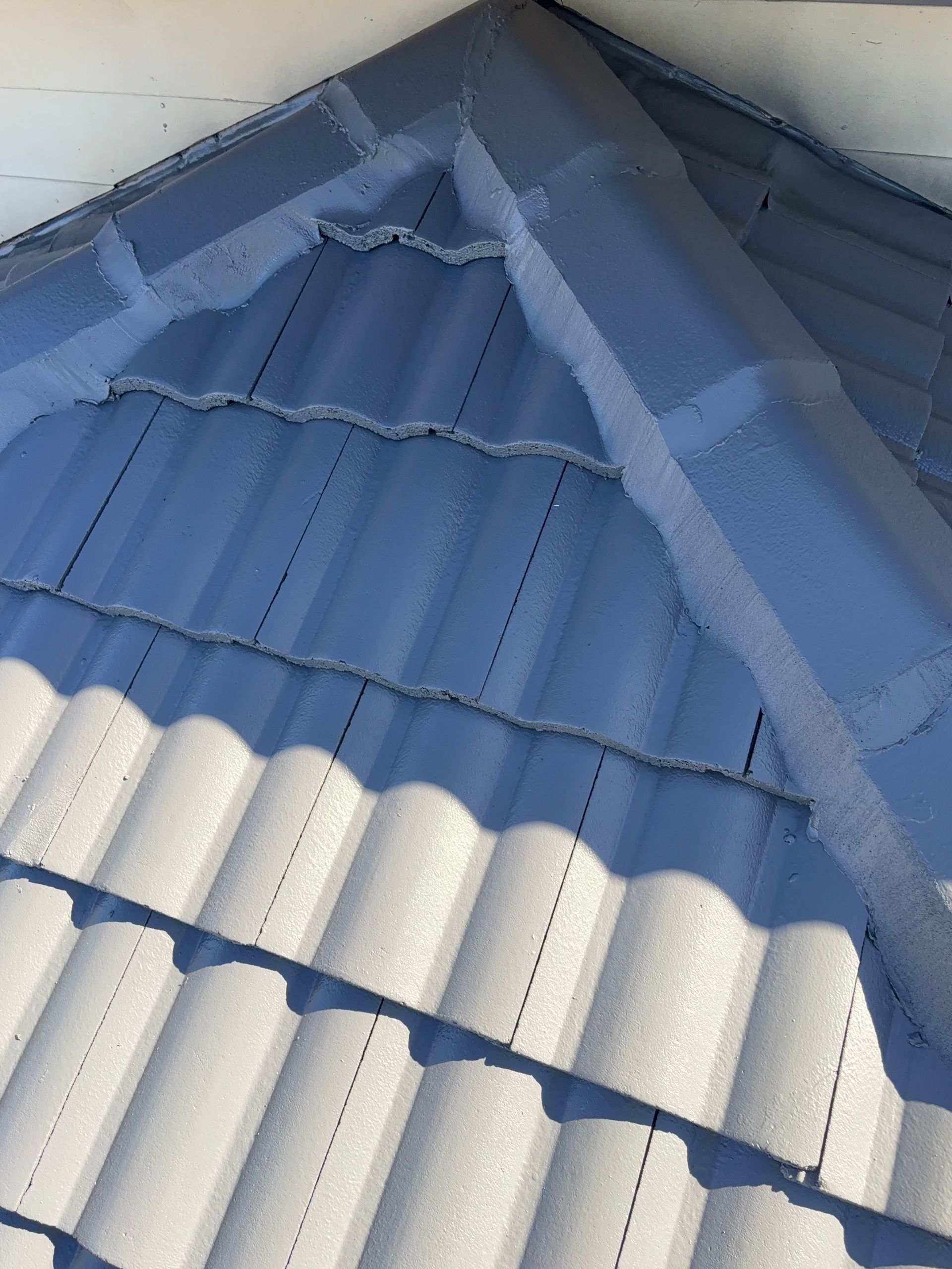 Blue and white metal roof with a steep triangular gable and sunlight casting shadows — In-Time Roofing In Newcastle, NSW