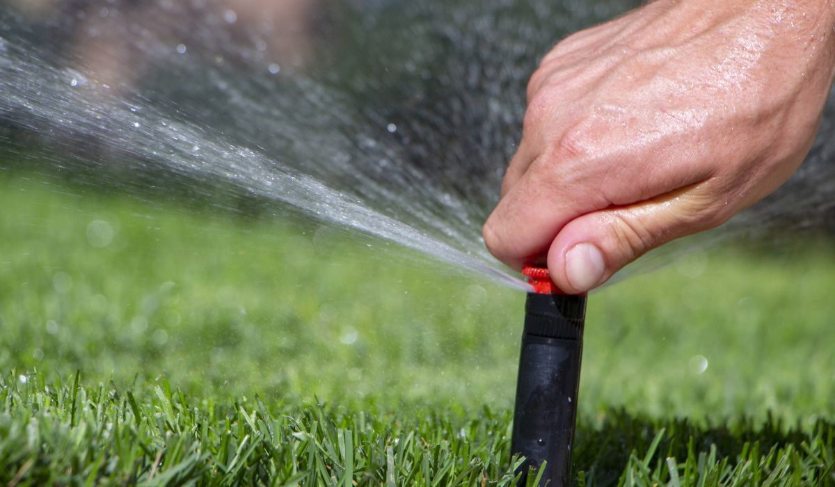 A person is watering a lawn with a sprinkler.