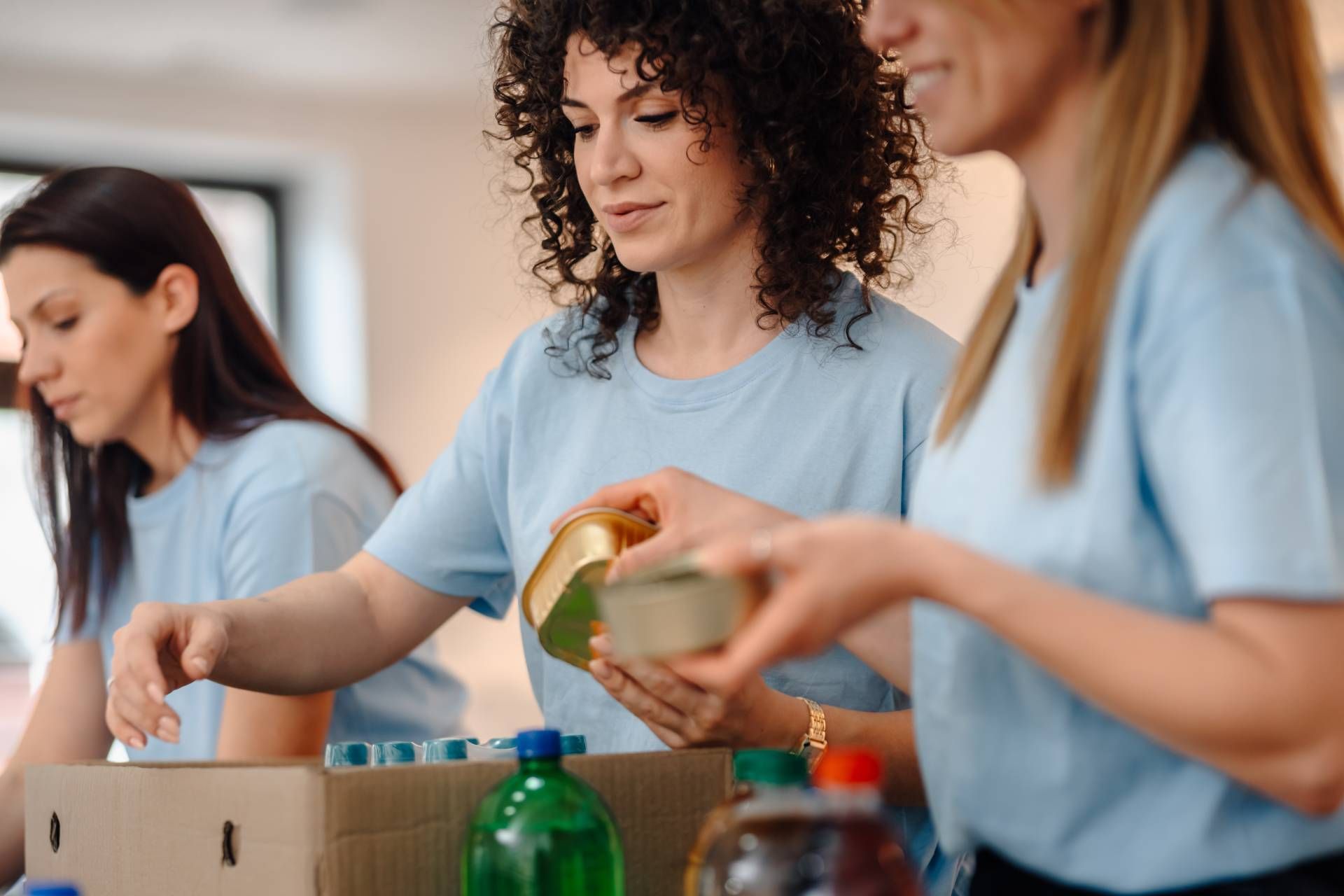 Volunteers sorting canned goods and bottles at a food drive table