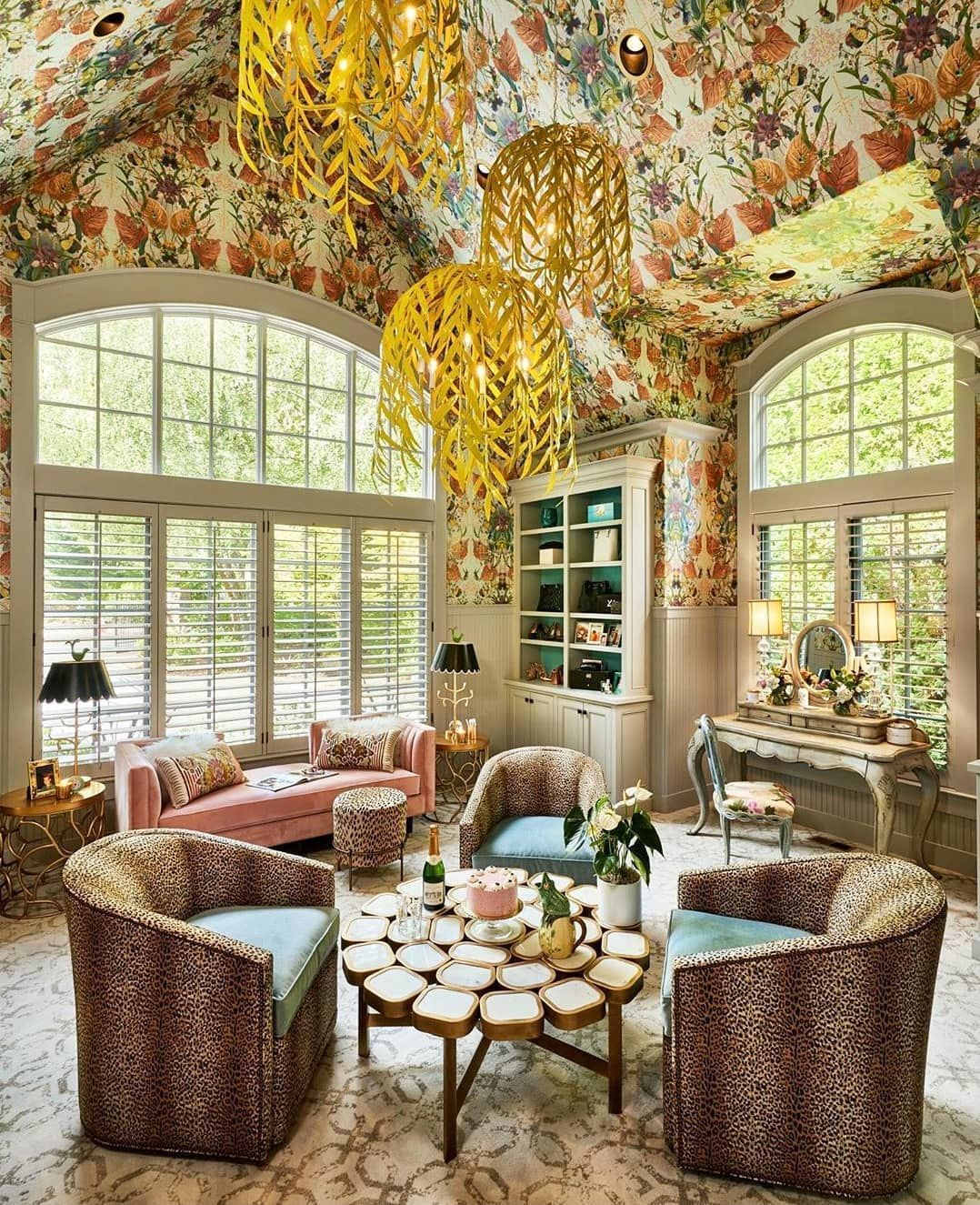 A living room with a couch , chairs , a table and a chandelier hanging from the ceiling.