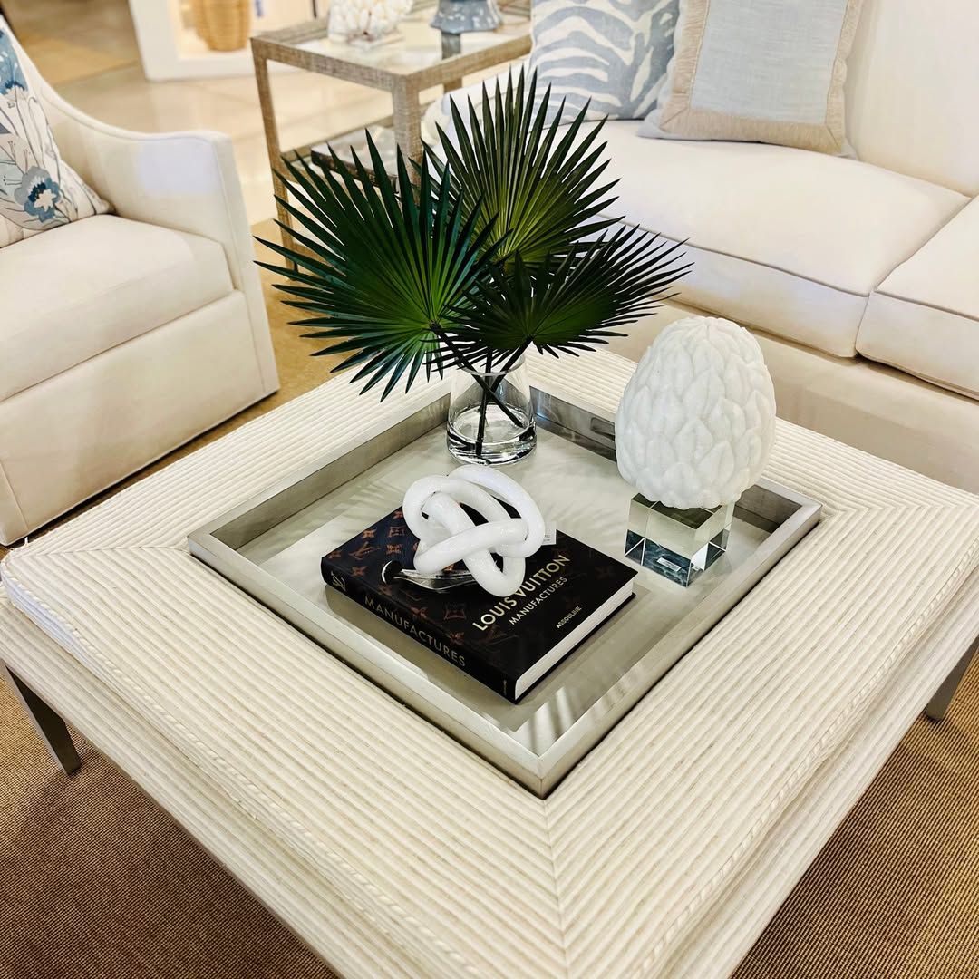 A coffee table with a tray and a book on it in a living room.