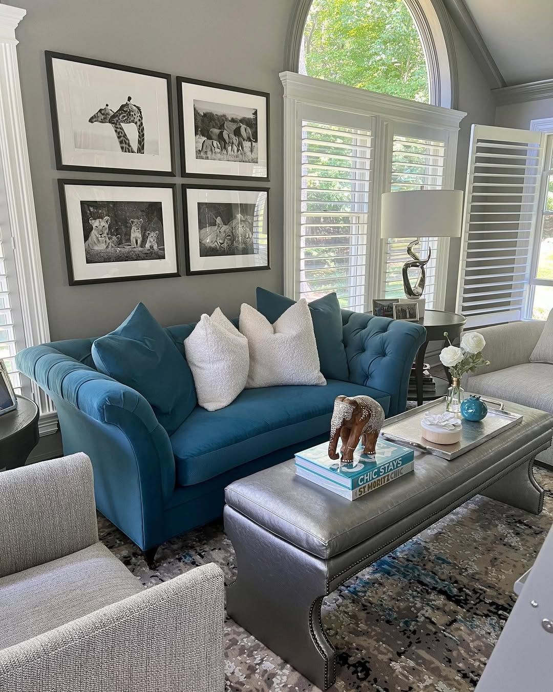 A living room with a blue couch , gray chairs , and a coffee table.